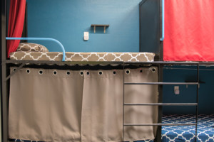 Bunk beds with privacy curtains and personal outlets at California Dreams Hostel