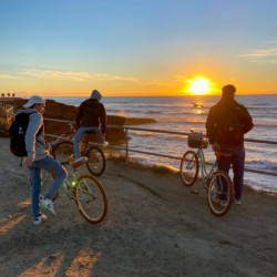 Travelers with bikes watching the sunset by the ocean in San Diego