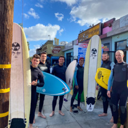 Group of travelers with surfboards outside a surf rental shop in San Diego